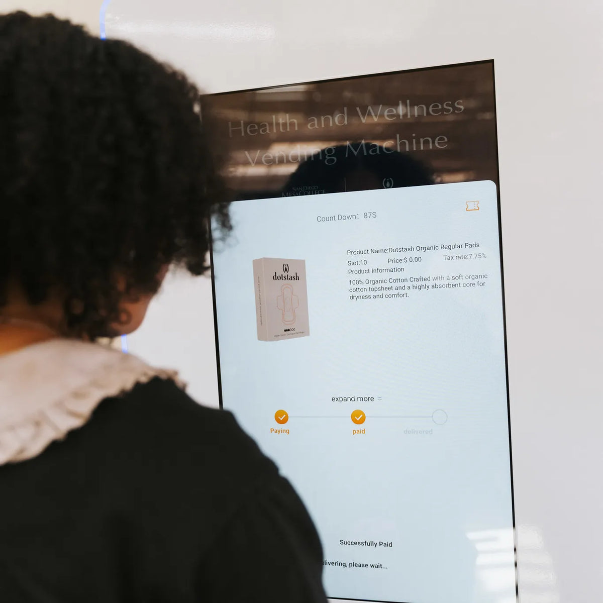 Student using Dotstash campus wellness vending machine offering affordable health products.
